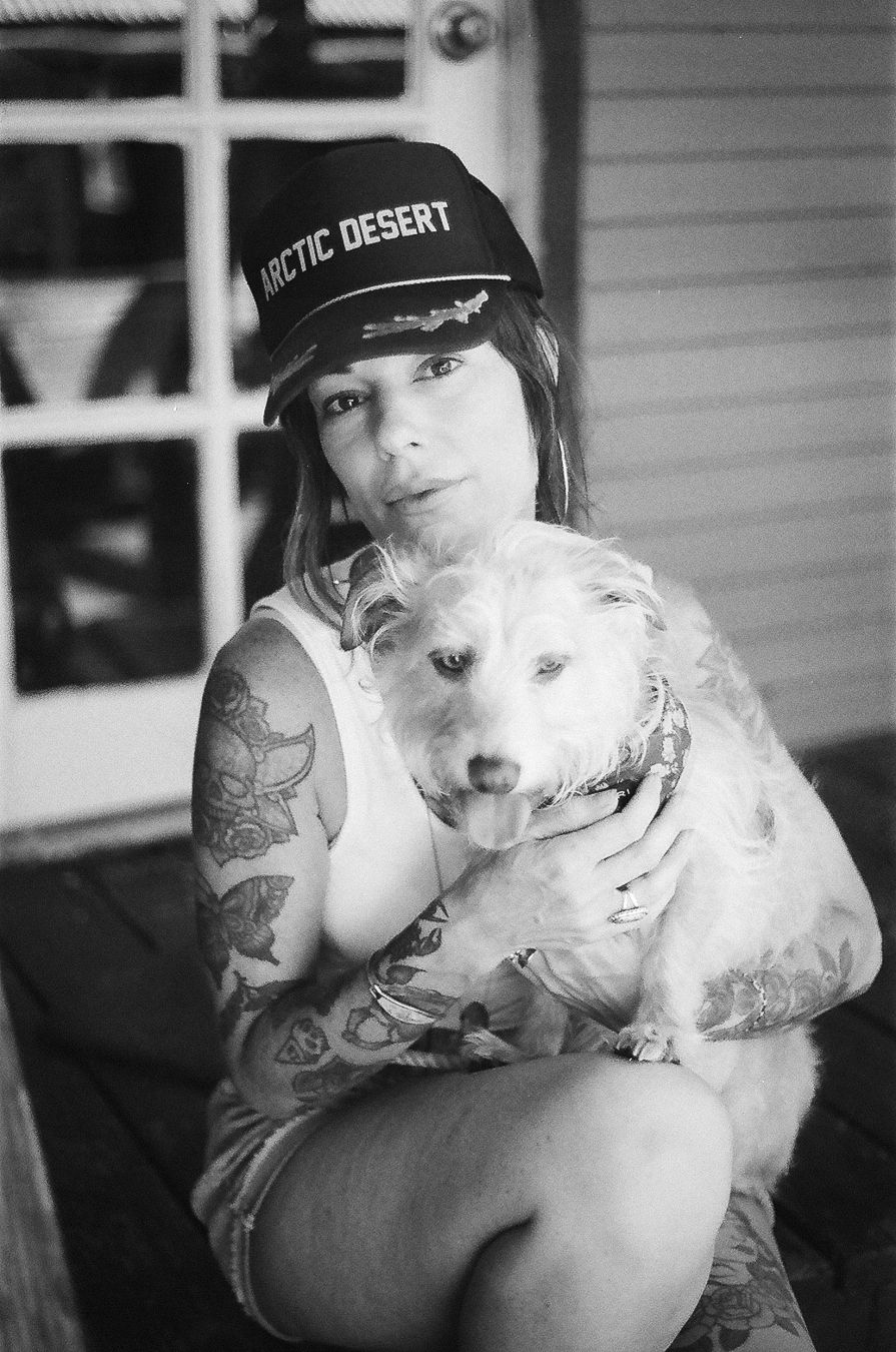 A series of black and white photos showing someone in a cap holding and cuddling with a white pit bull dog.