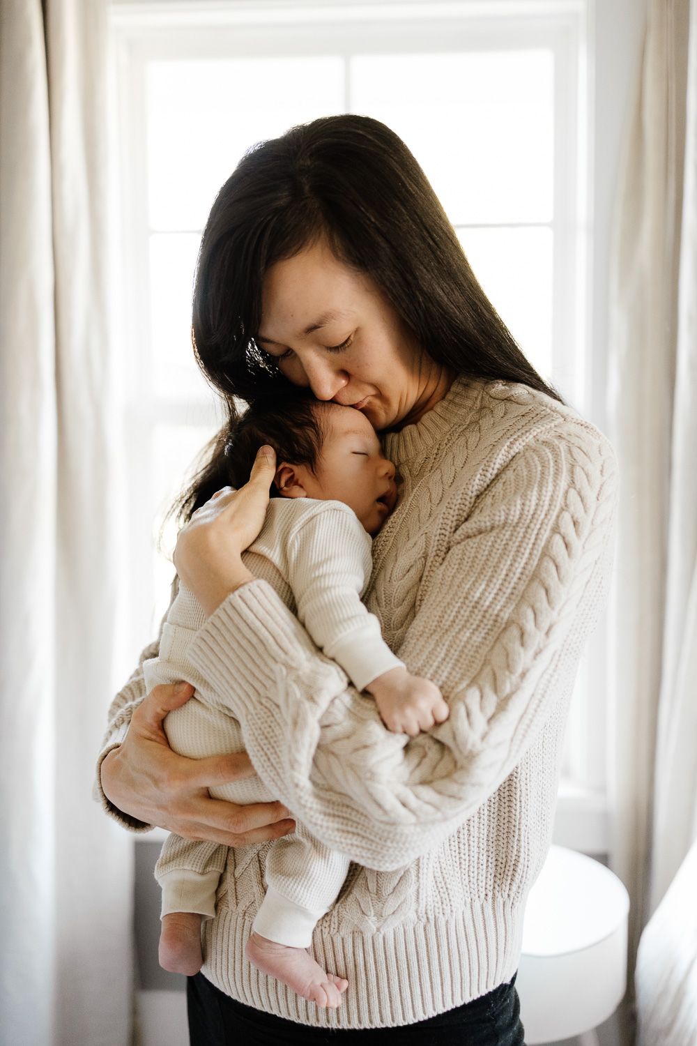 Mom kisses baby's head at their newborn in-home photography session in San Jose
