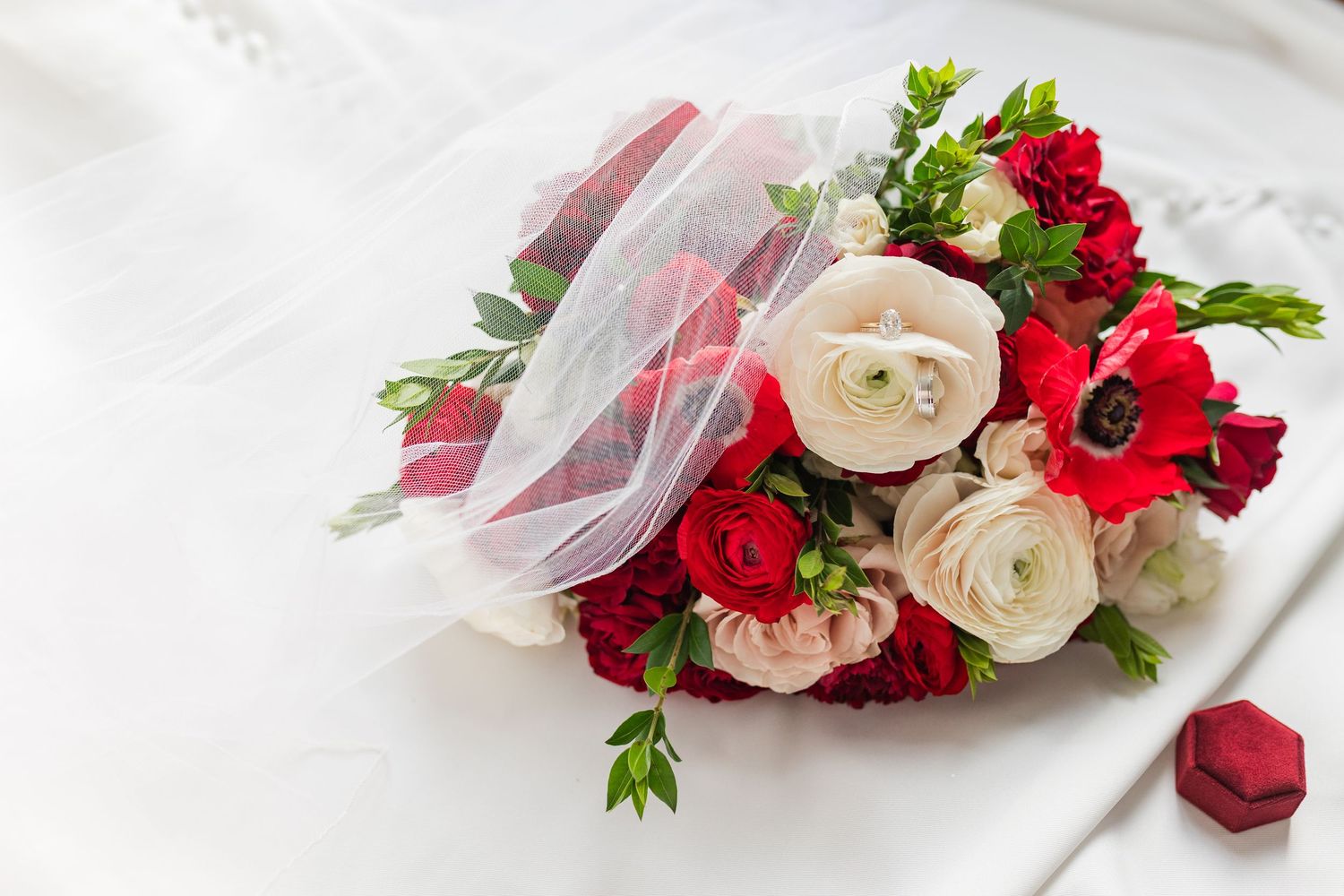 A delicate bridal hair comb adorned with red and white roses and greenery against a light background.