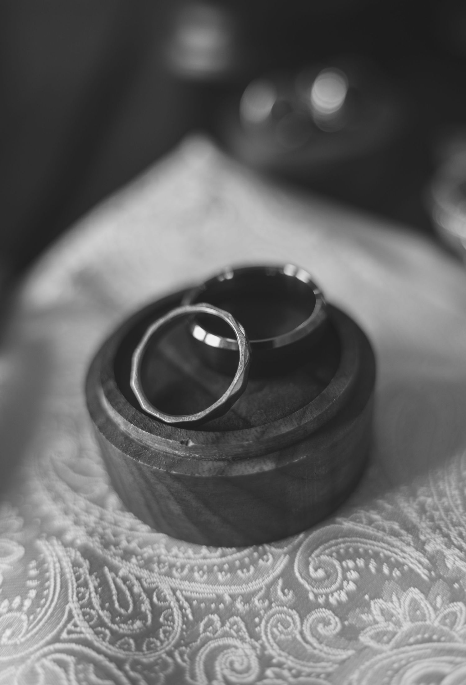 Wedding rings displayed on a decorative wooden box with lace pattern.