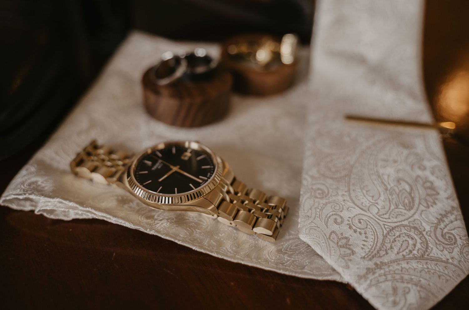 Wedding details including rings, invitations, and delicate floral arrangements on a white lace tablecloth.