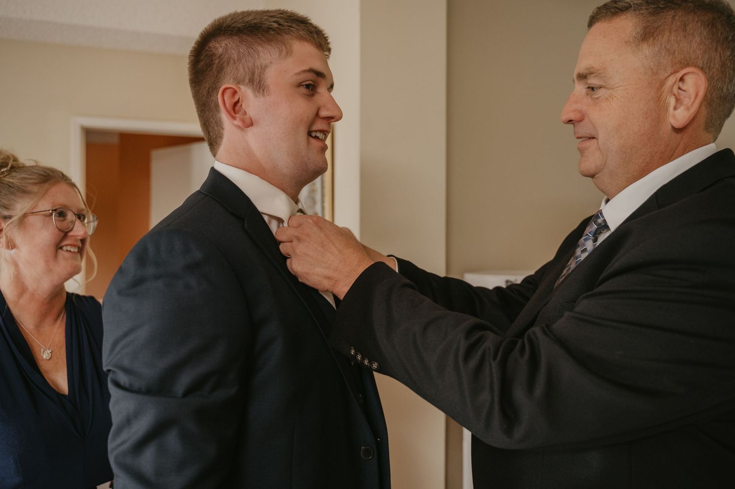 A group of men in formal attire helping each other get ready for a special occasion.