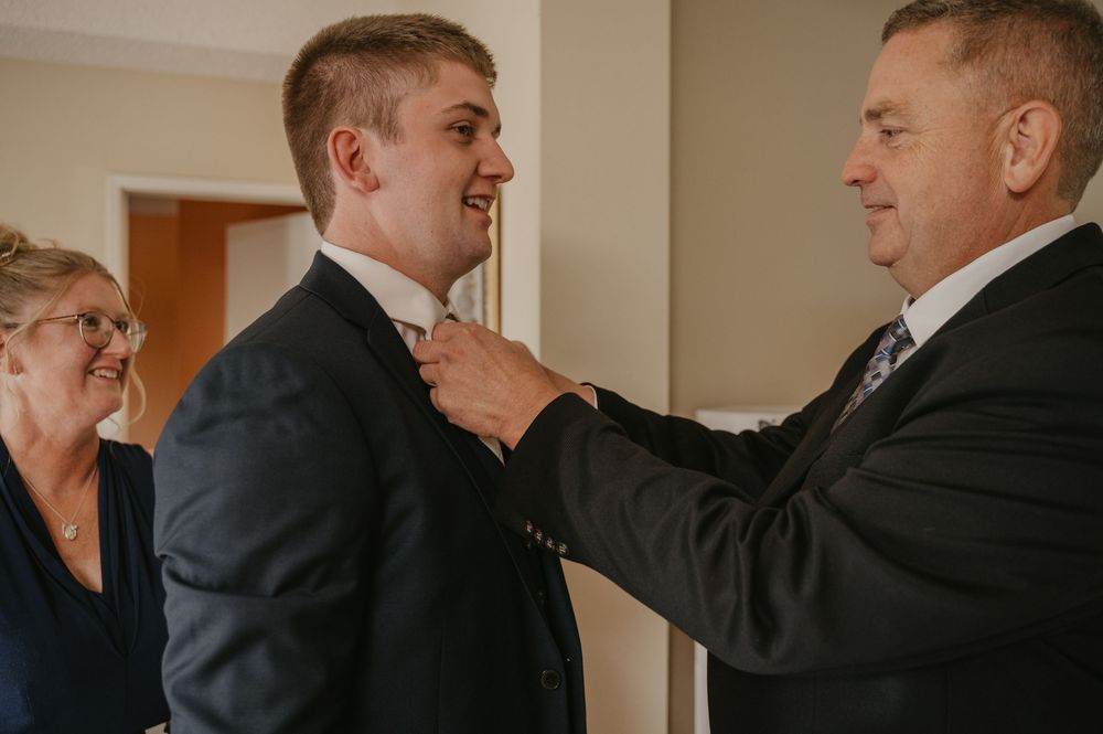 A group of men in formal attire helping each other get ready for a special occasion.