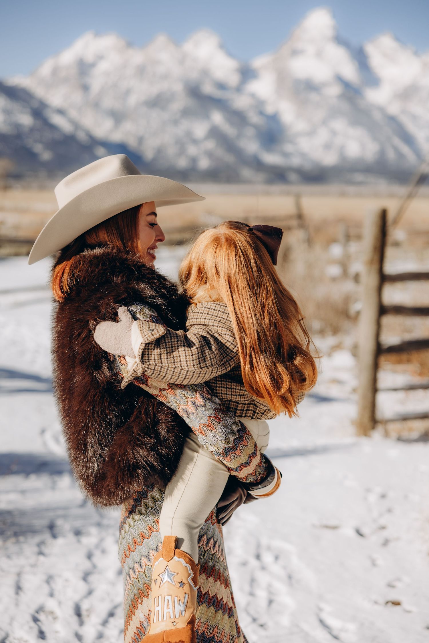 A romantic winter photoshoot with couples embracing in the snow with mountains in the background.
