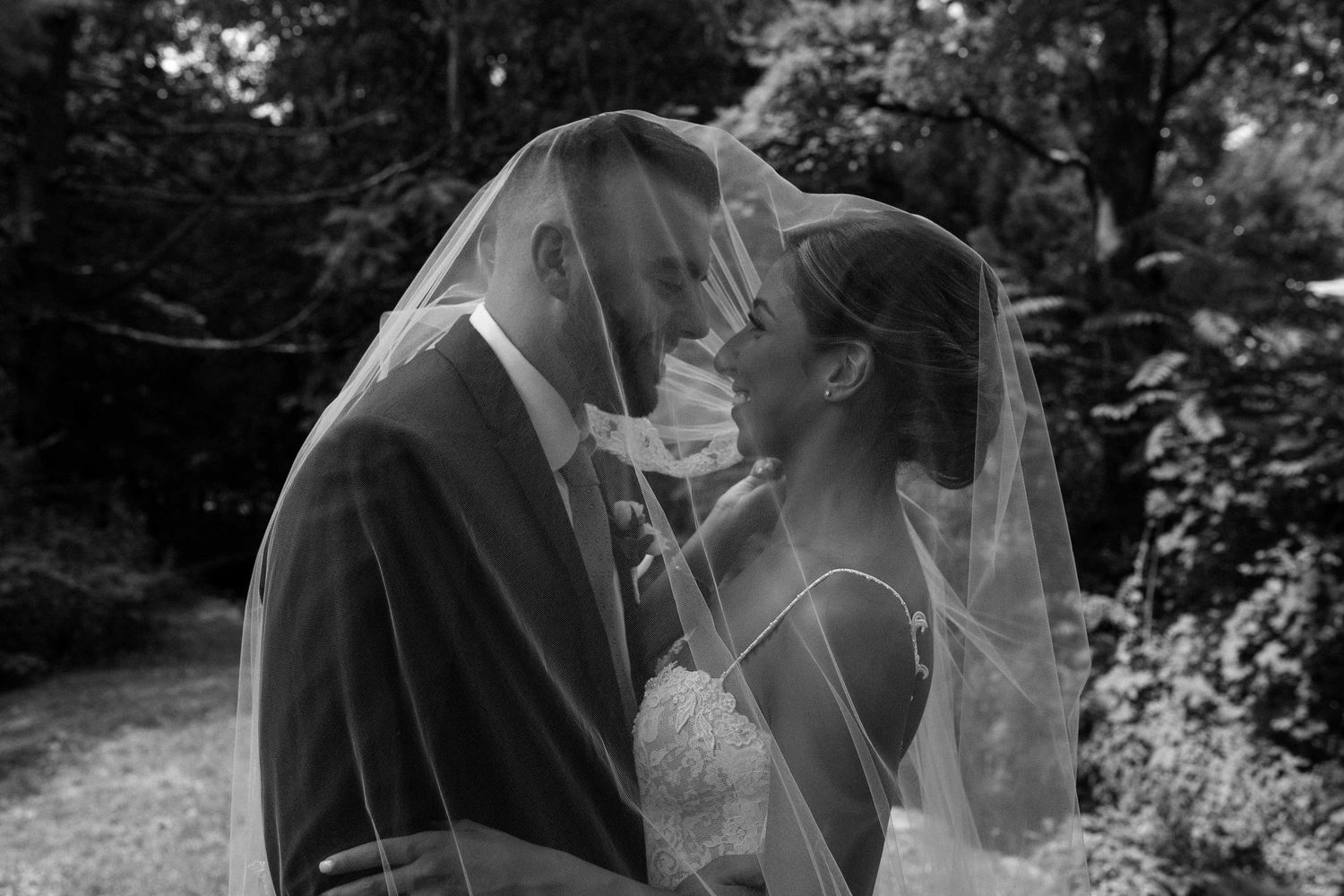 A romantic black and white wedding photo series showing intimate moments between a bride and groom in a garden setting.
