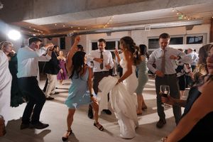 Wedding guests dance and celebrate on a spacious dance floor during an indoor reception party.