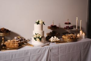 Rustic dessert table with stacked waffles, pastries and white floral arrangements on a white tablecloth.