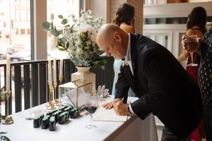 People dining and socializing at a restaurant bar counter with wine bottles and glasses visible.