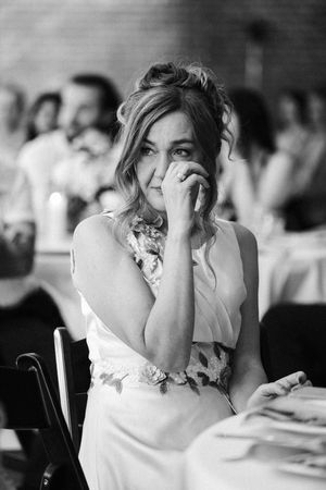 Black and white photo of an emotional guest in a white dress at a wedding reception.