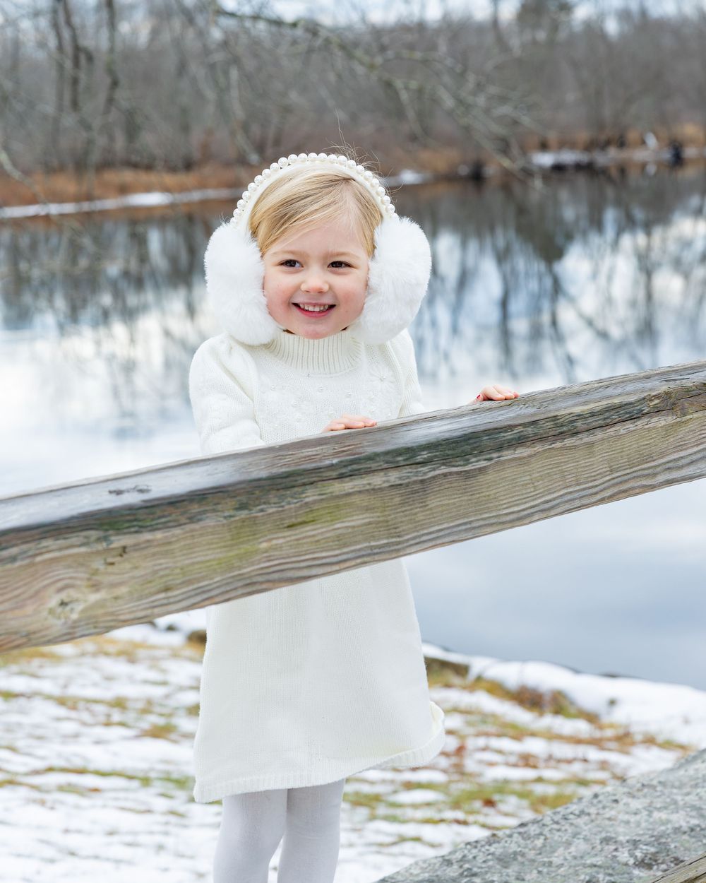 A young girl poses on Old North Bridge during a bright afternoon during winter family photography session in Concord, MA. Bolton