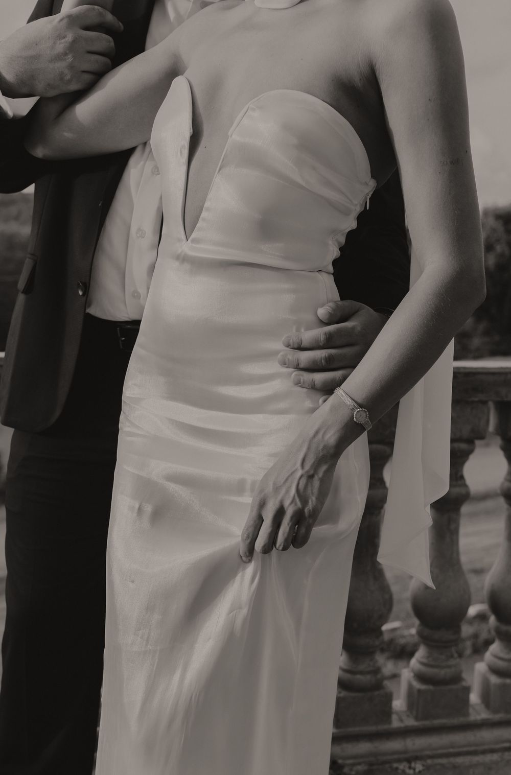 Black and white photograph of a person in an elegant formal white dress with empire waist silhouette.