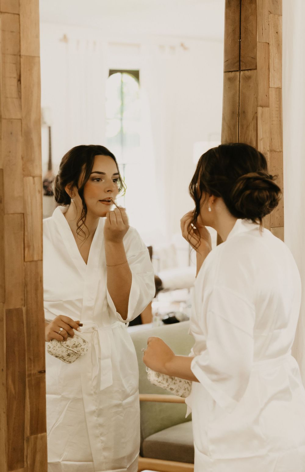 Women in white robes gather in a warm-toned room preparing together before an event.