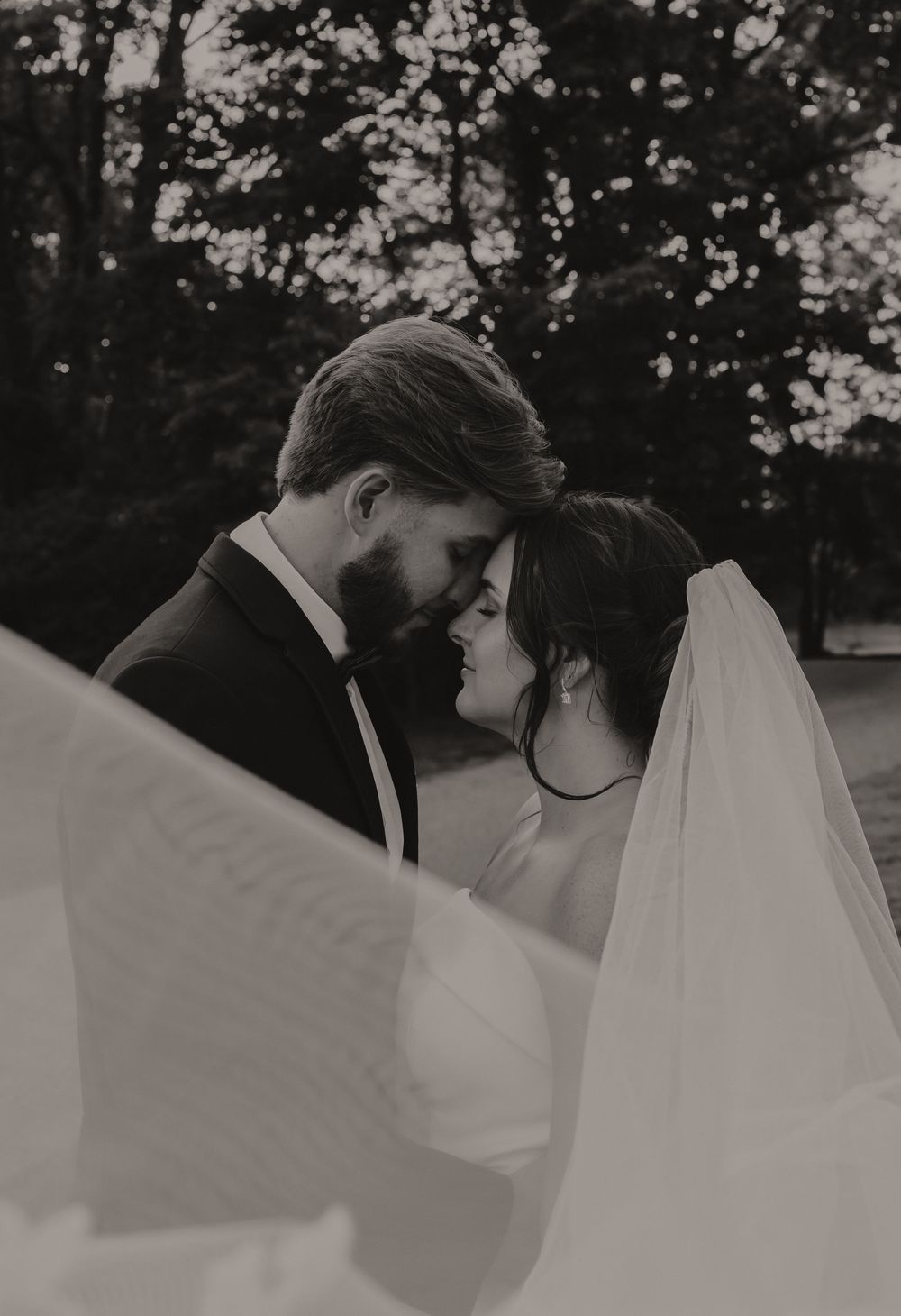 A series of romantic black and white wedding photos showing intimate moments between a couple with flowing white veil details.