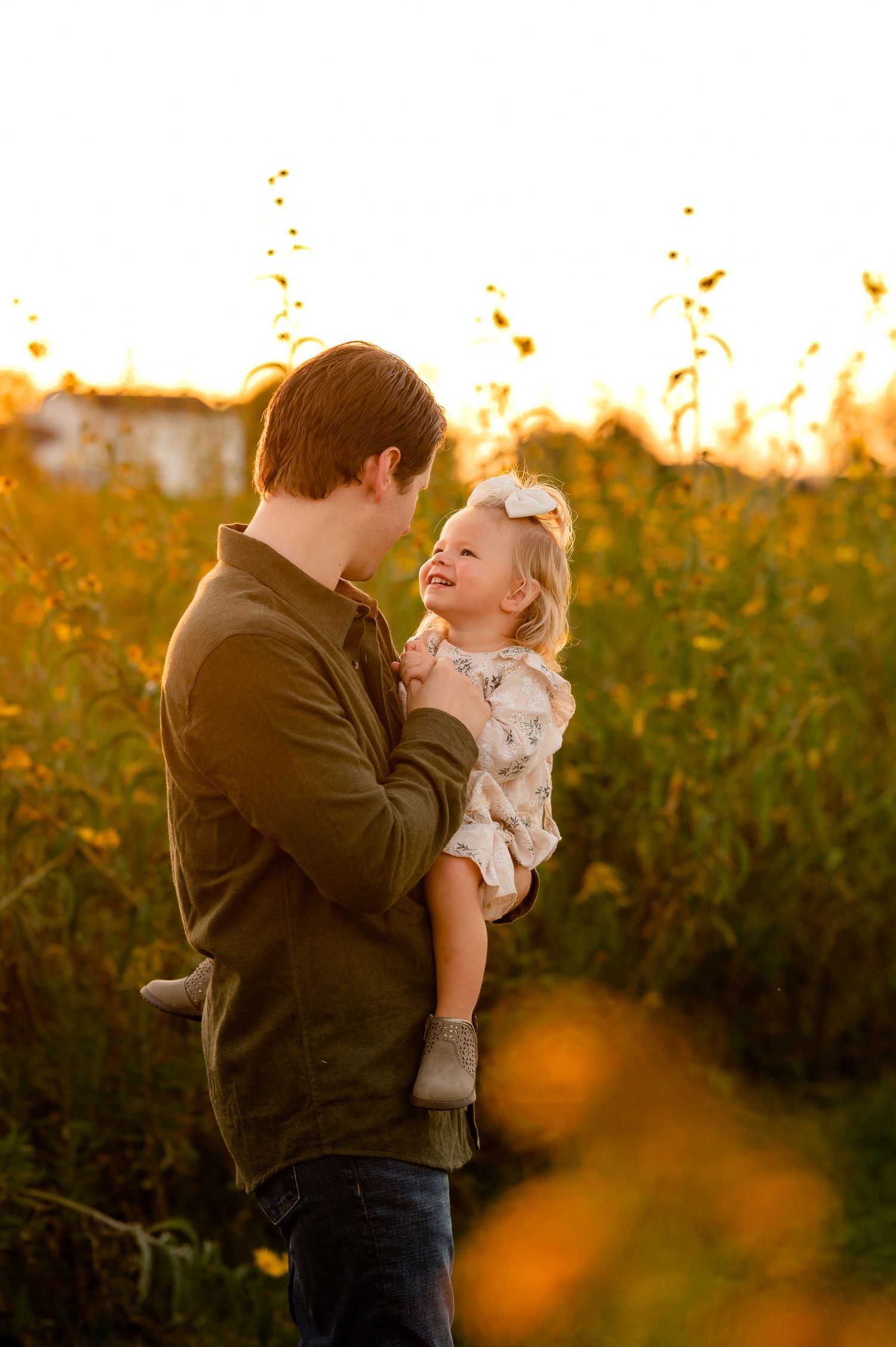 Father holding daughter captured against a glowing sunset backdrop created by Storms Photography in Pennsylvania.