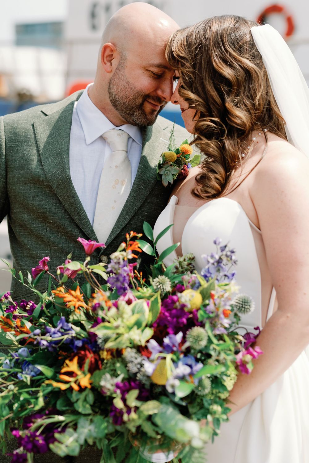 A romantic wedding moment featuring a vibrant wildflower bouquet with purple, orange and blue blooms.