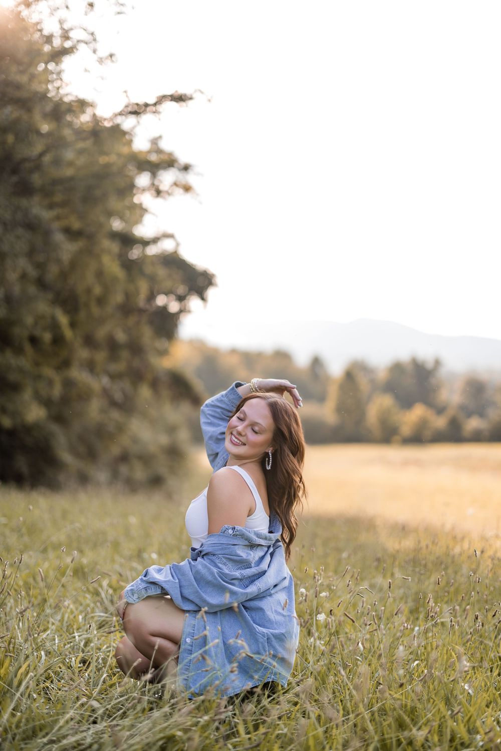 A carefree summer portrait in a golden meadow with denim and white casual attire during golden hour.