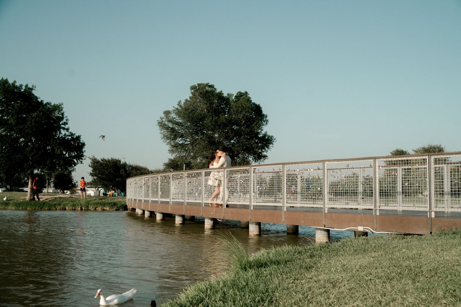 A long bridge extends over water with decorative railings during sunset.