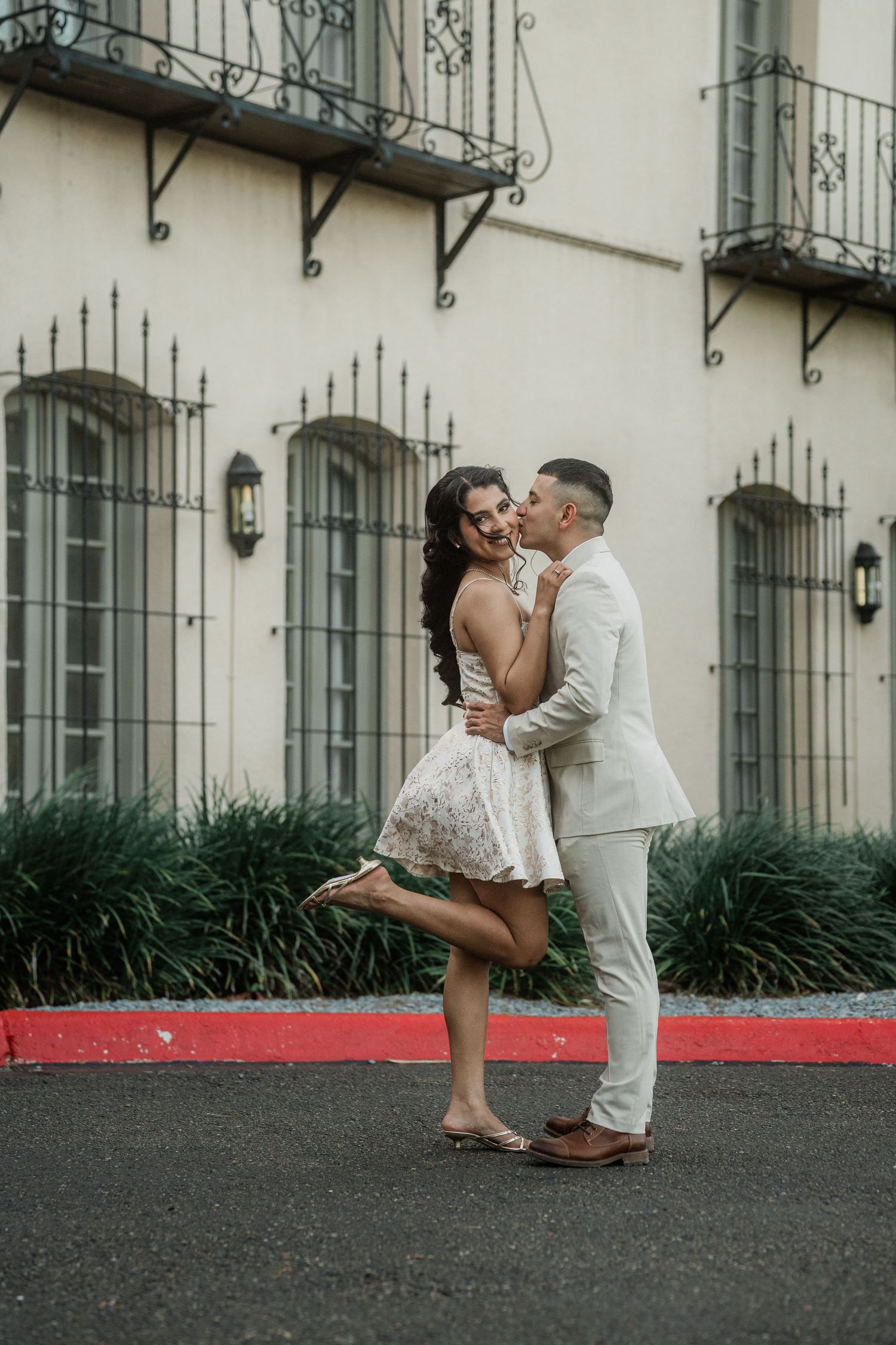 A romantic scene unfolds against an elegant building facade with wrought iron details.