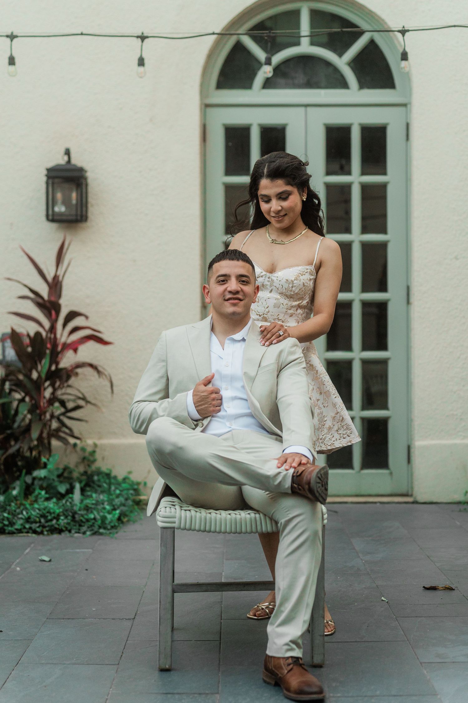 A playful moment captured on a stone patio in front of arched turquoise doors.