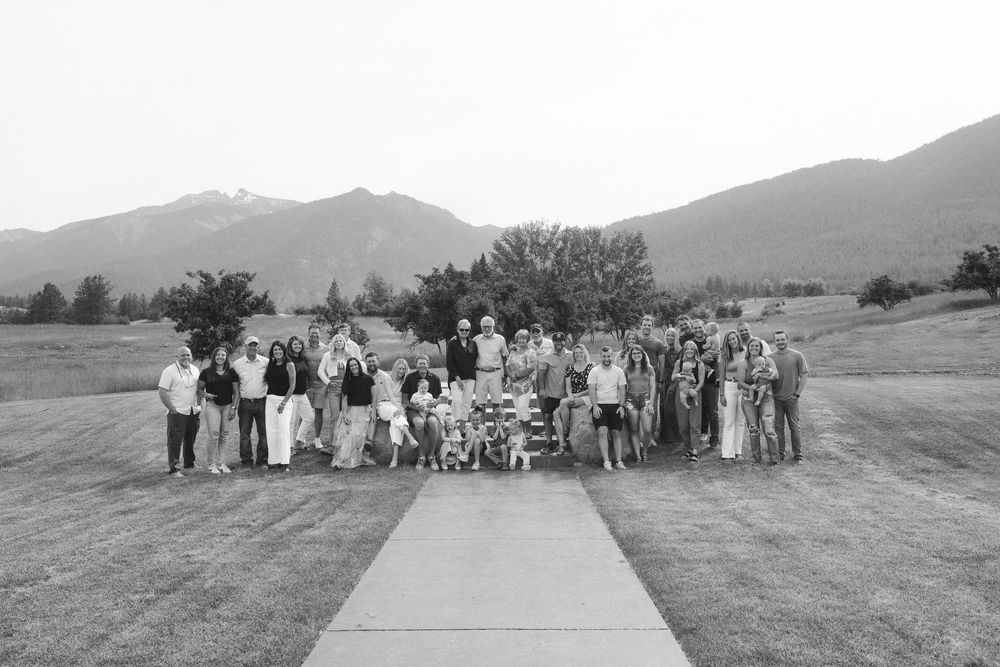 Panoramic view of a large family gathering in an open field with mountains in the distance.