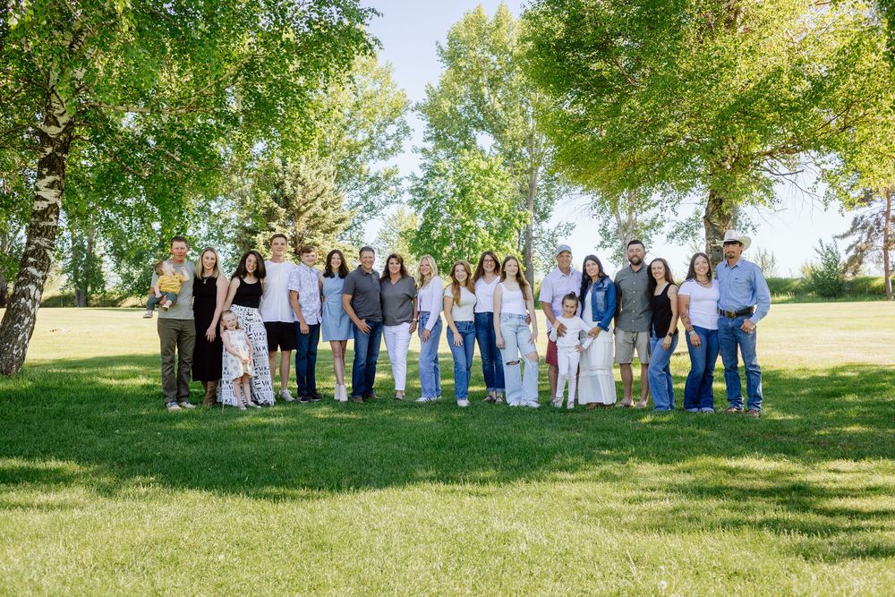 Extended family group portrait on a sunny day with lush green trees in the background.