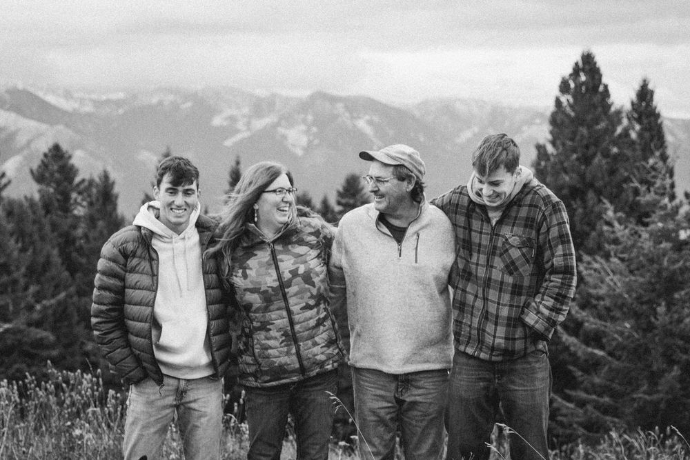 Family group photo session with mountain landscape backdrop.