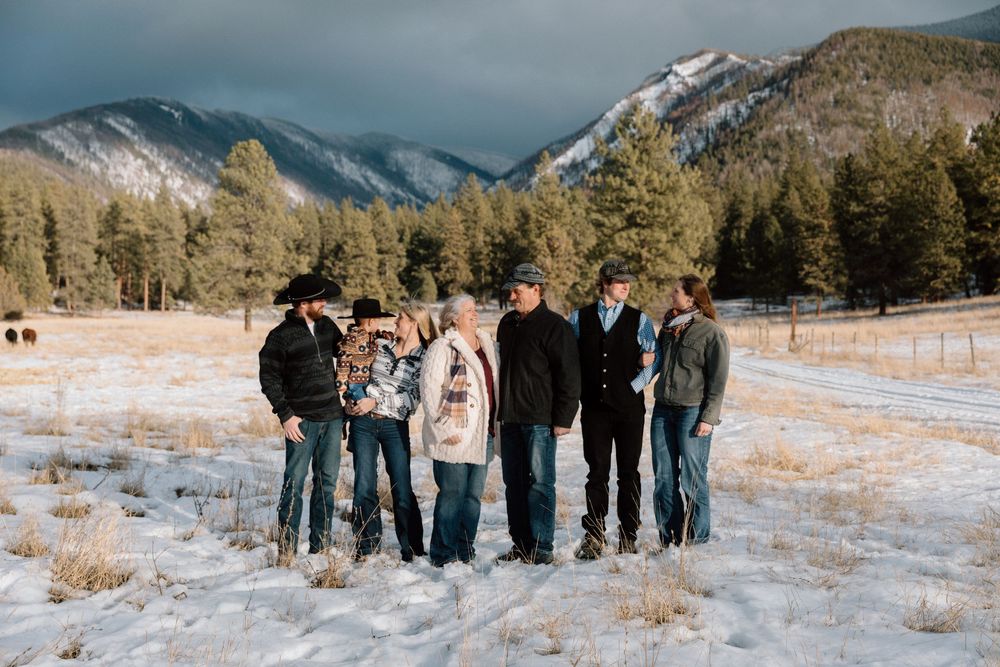 Group photo of people gathered in snowy field with mountains in background.