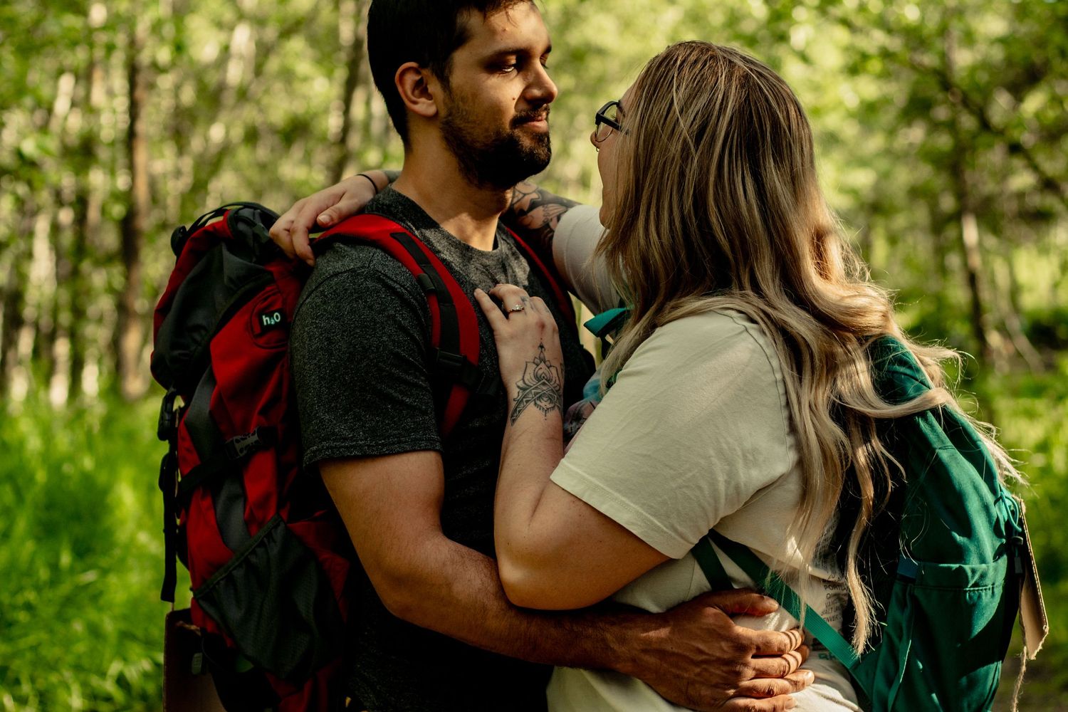 Hikers on a forest trail wearing backpacks with paper signs attached to their packs.