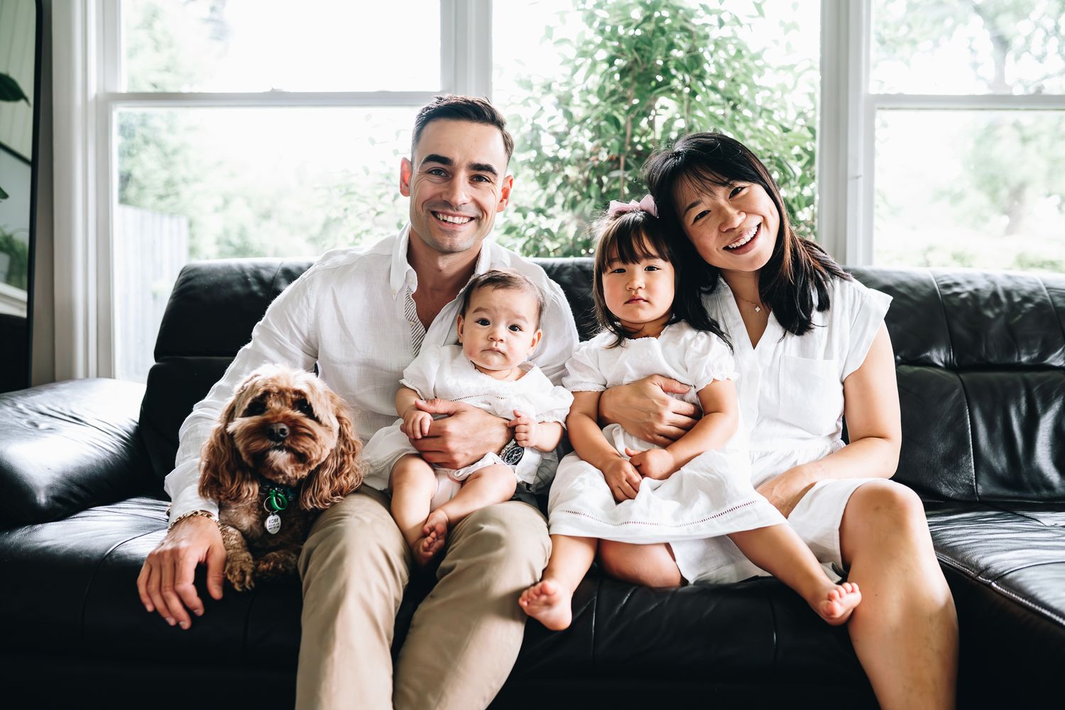 A family relaxes together on a cozy gray couch with their brown dog during a family portrait photo session in Melbourne.