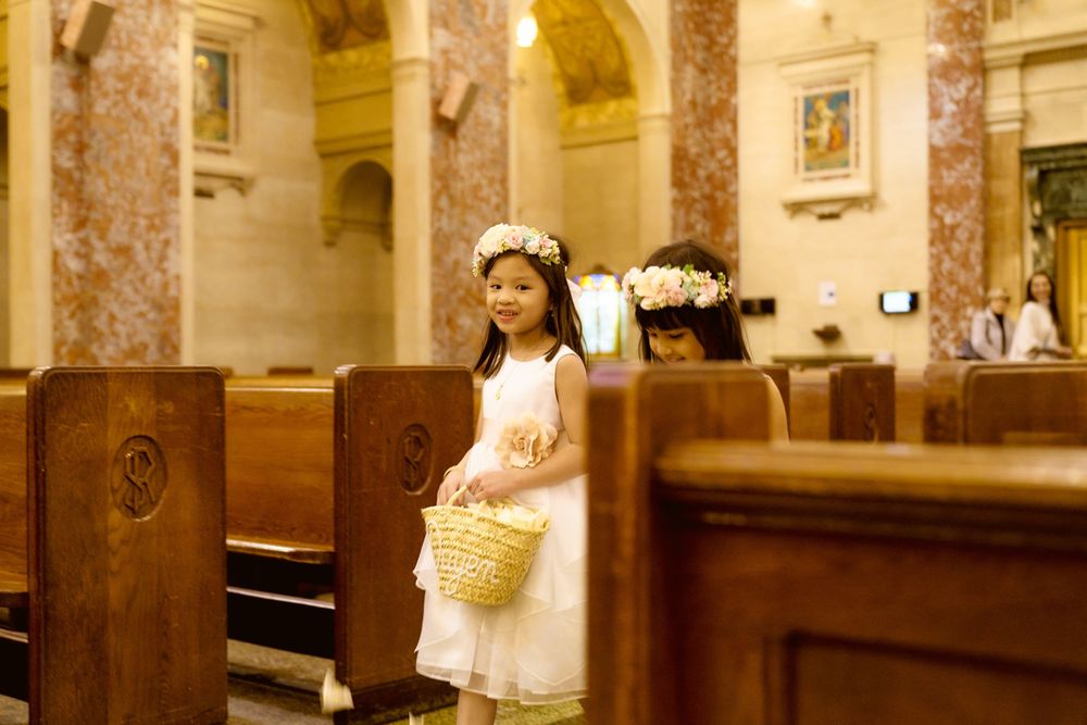 Young attendee in white dress standing beside wooden church pews.