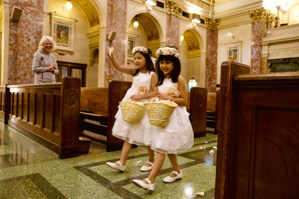 Two attendees in white dresses walking through church sanctuary aisles.