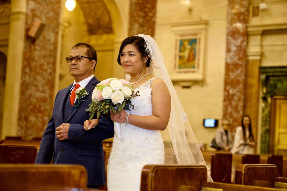 An intimate moment during a church ceremony as a couple stands together with white floral bouquet.