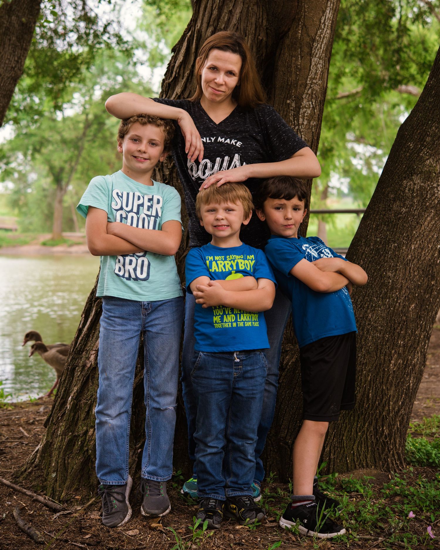 Collection of children wearing casual t-shirts posing together near wooden railings outdoors.
