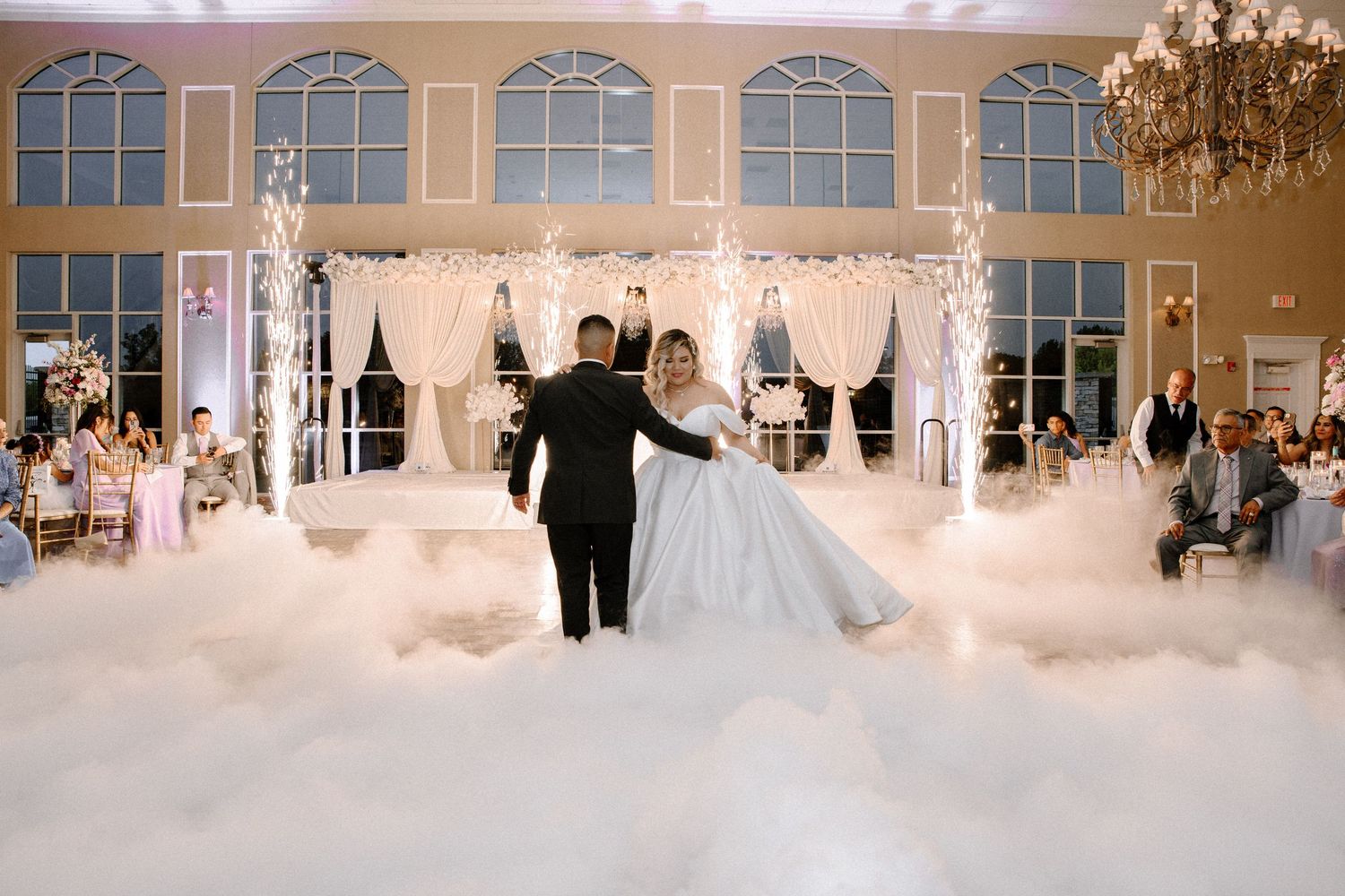 Elegant bridal gowns are displayed in a bright, spacious wedding boutique showroom with arched windows and modern decor.
