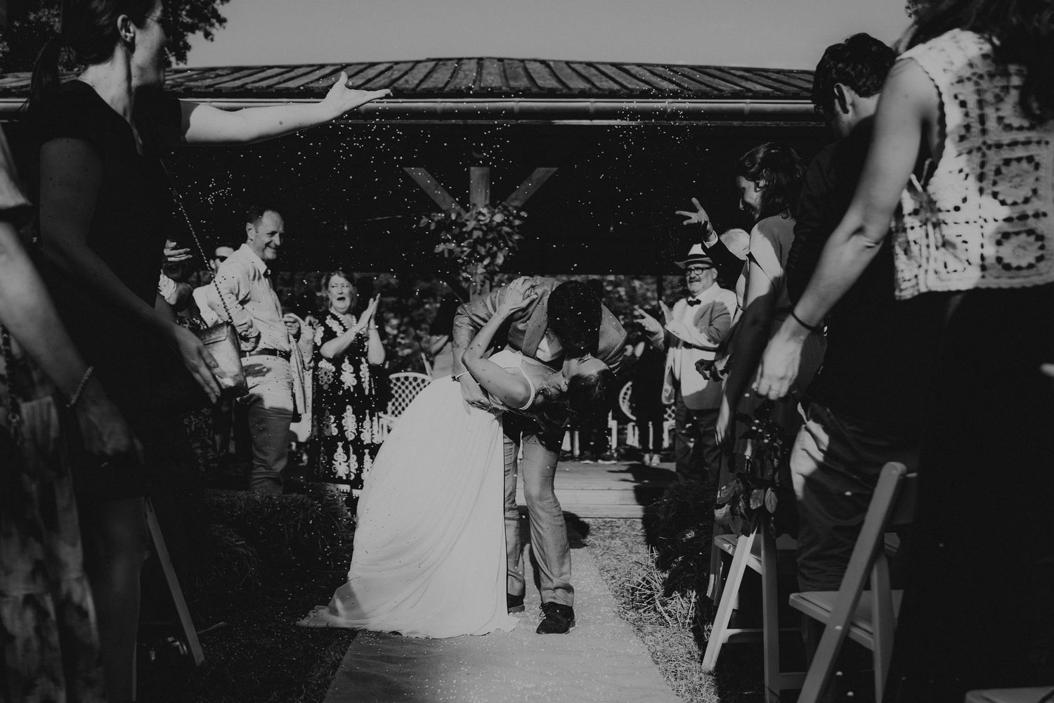 A romantic black and white wedding photograph showing a tender embrace in a natural outdoor setting.