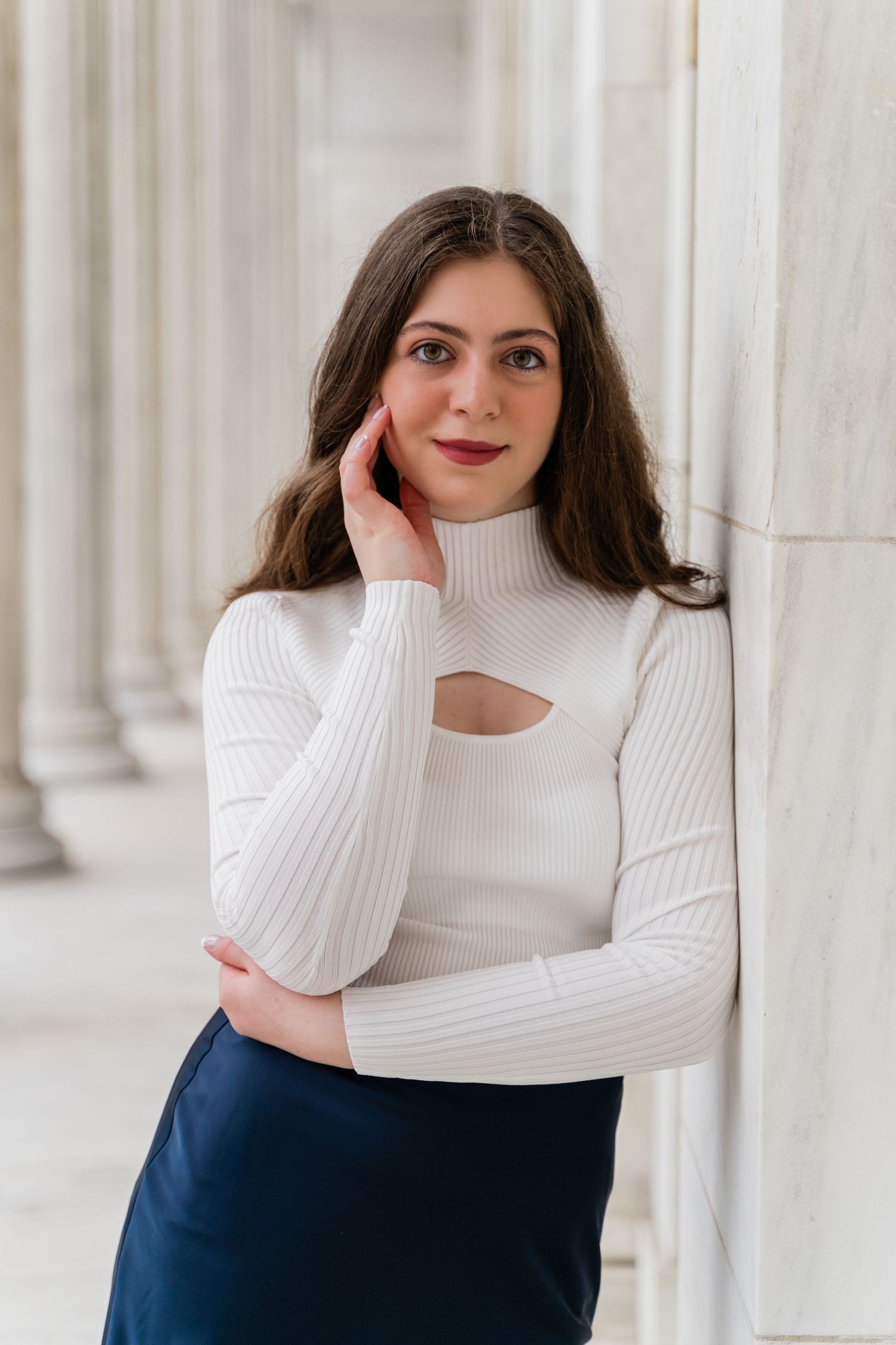 Perrysburg senior poses at Toledo Museum of Art featuring a white cutout turtleneck sweater and navy skirt against classical columns.