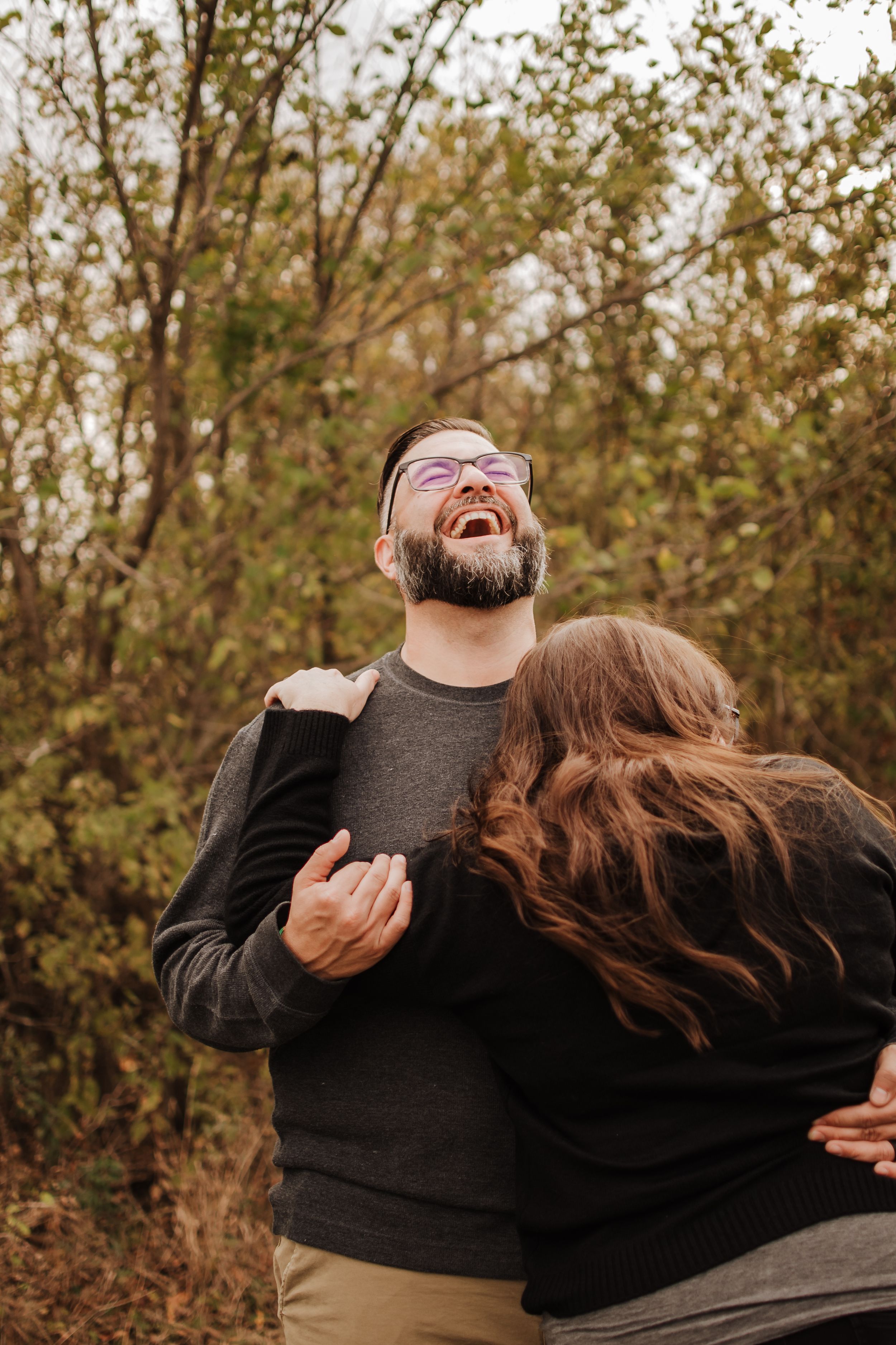 A joyful moment of laughter shared between a couple in an autumn setting.
