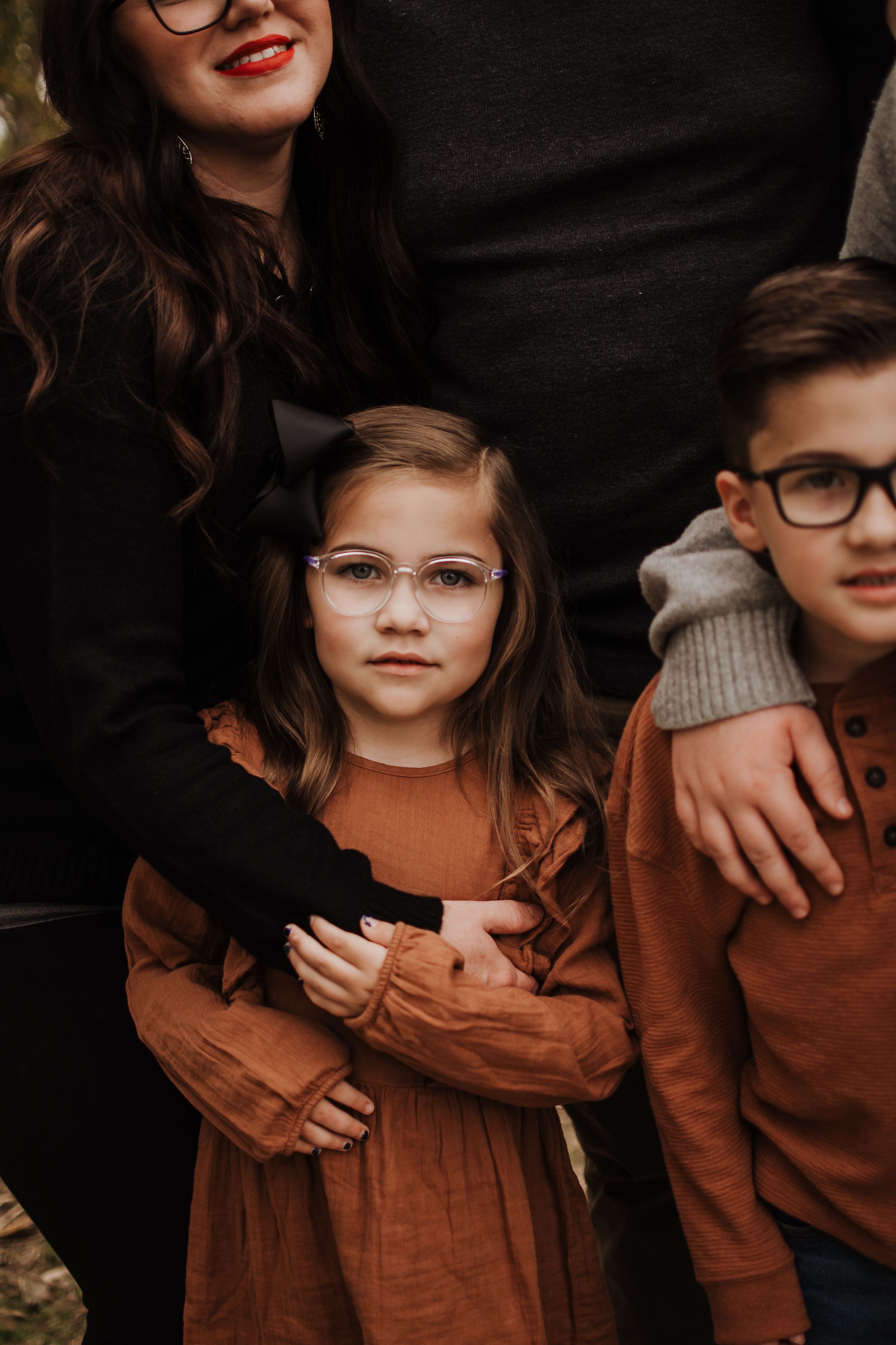 A close family portrait showcasing coordinated autumn outfits and warm embraces.