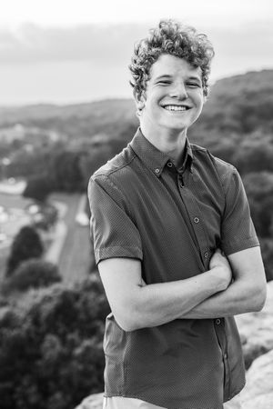 Black and white portraits capture joyful expressions and crossed arms against a scenic outdoor backdrop.