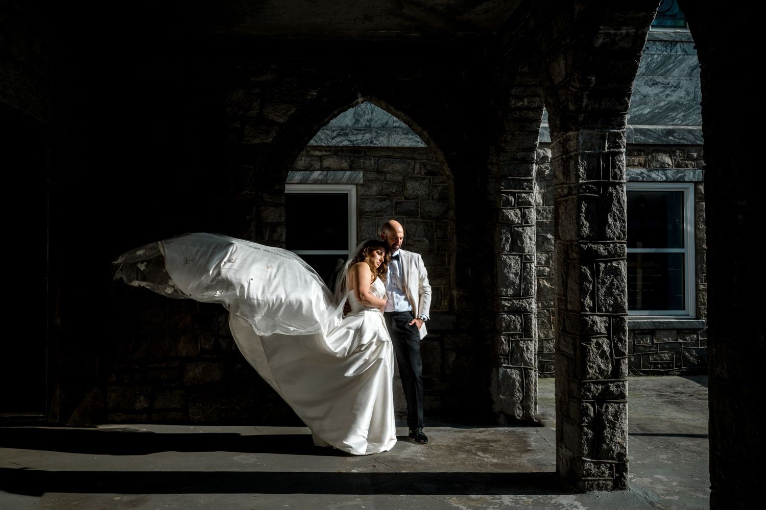 Artistic bridal portraits with dramatic shadows and light against stone architecture.