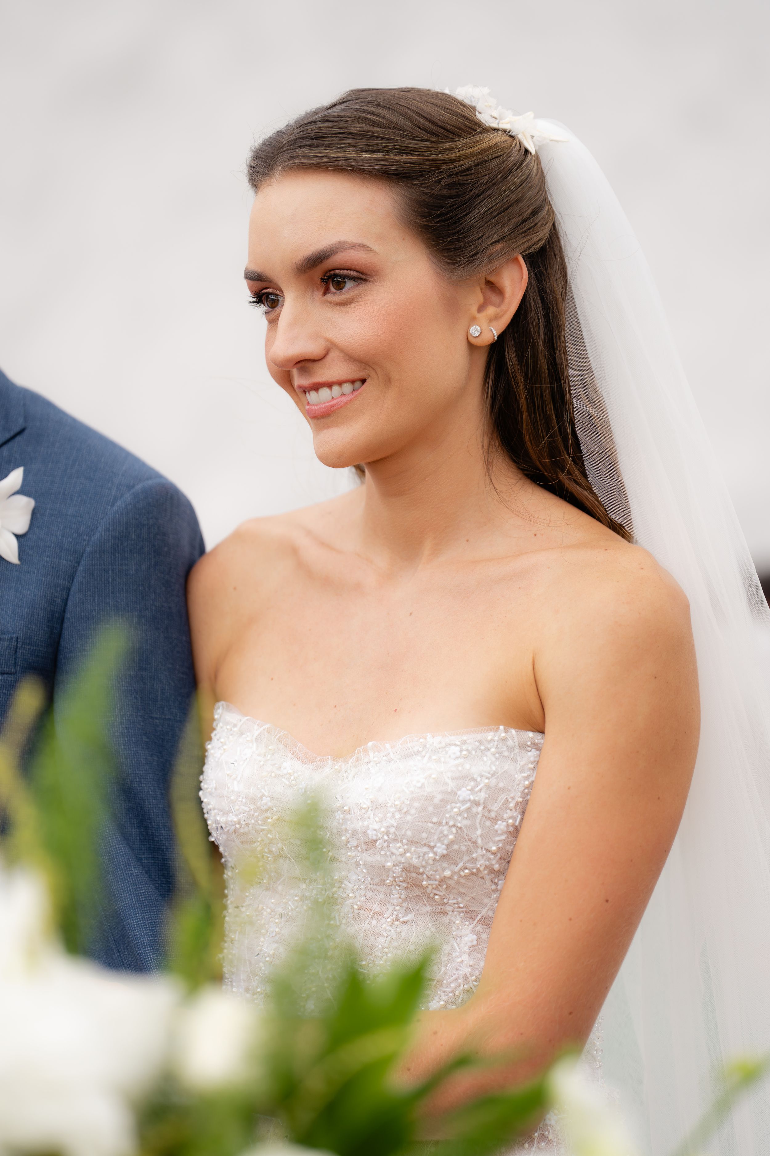 A bride wearing a strapless lace wedding dress smiles warmly during her wedding celebration.