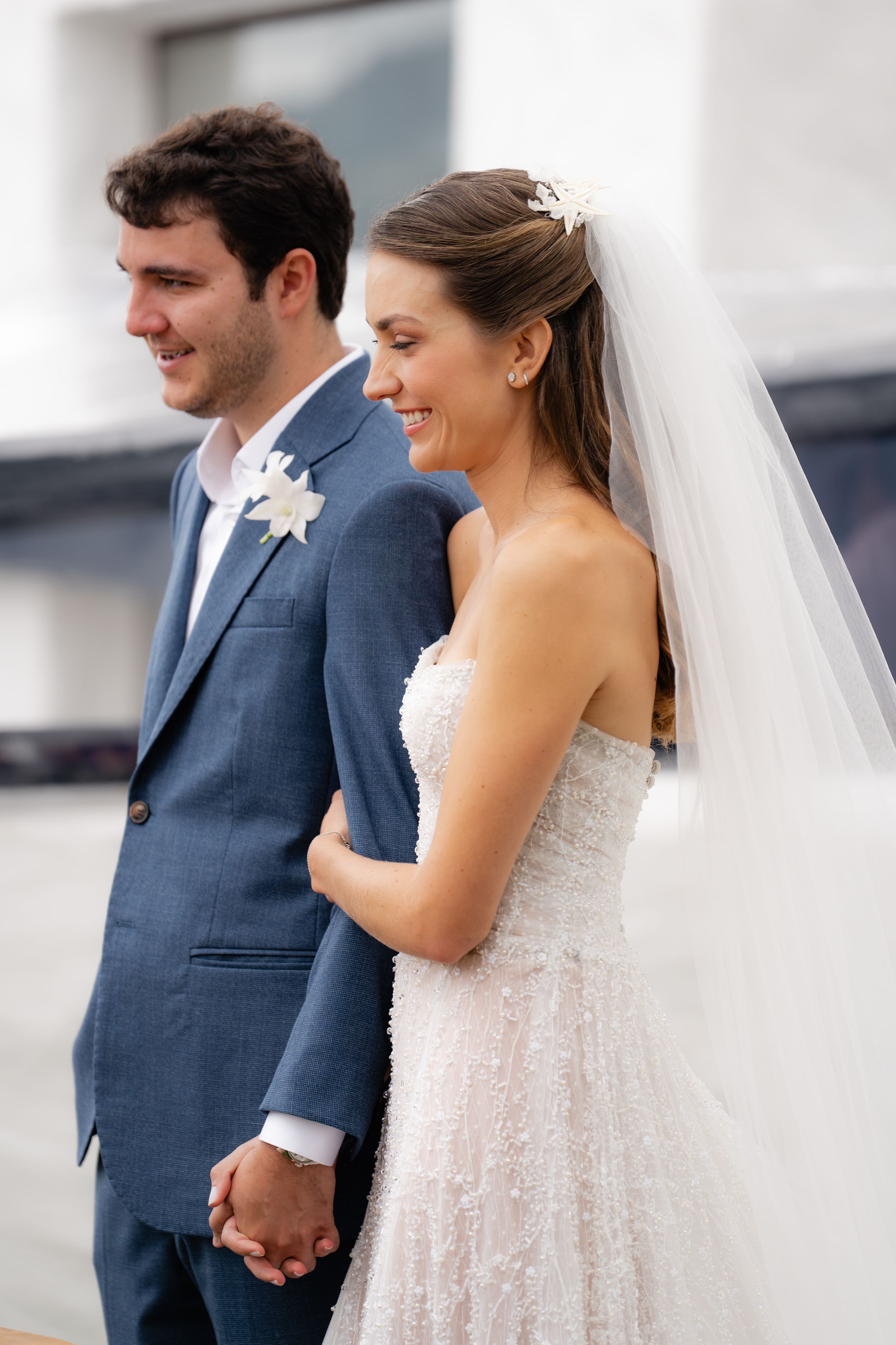A couple in wedding attire share intimate moments during a portrait session with the bride in a white lace gown.
