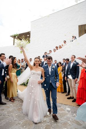 Wedding guests form a receiving line to shower the newlywed couple with flower petals and confetti during their exit.
