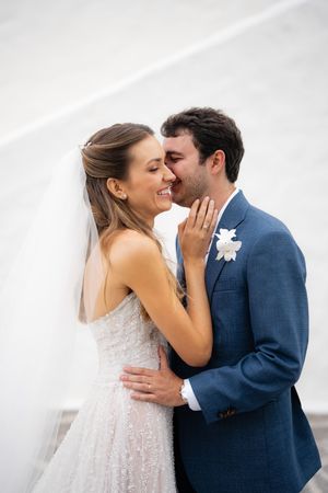 A bride and groom share an intimate moment against a white background during their wedding photoshoot.