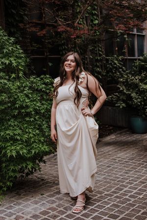 An elegant portrait in a flowing cream dress against a brick and ivy wall. Downton Fort Worth