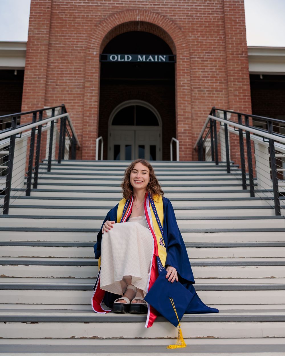 University of Arizona grad with cap and gown on campus – UArizona graduation pictures at Old Main