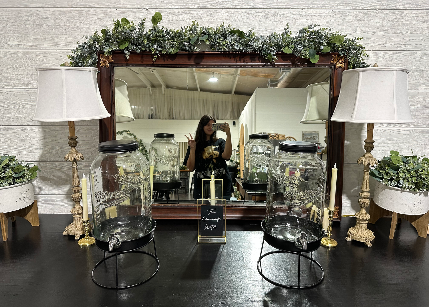 Woman taking selfie in the mirror behind the refreshment table at a wedding venue
