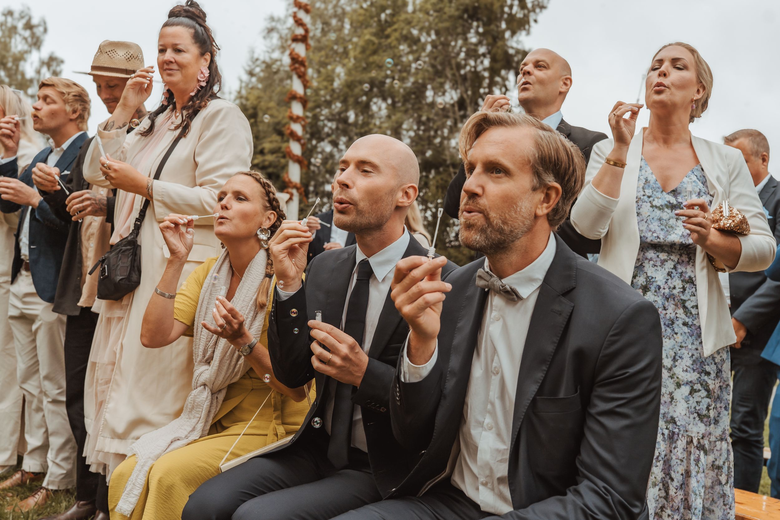 Wedding guests gather outside looking up at the sky during a celebratory moment at an outdoor reception.