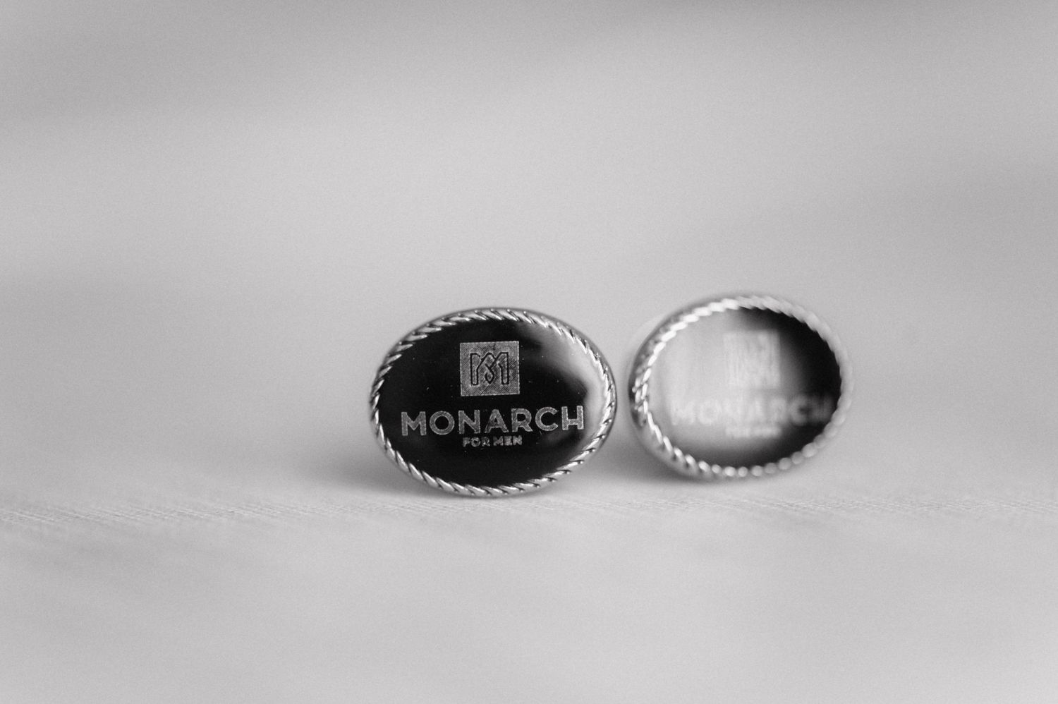 Black and white macro photo of two Monarch-branded bottle caps shown in close-up detail.