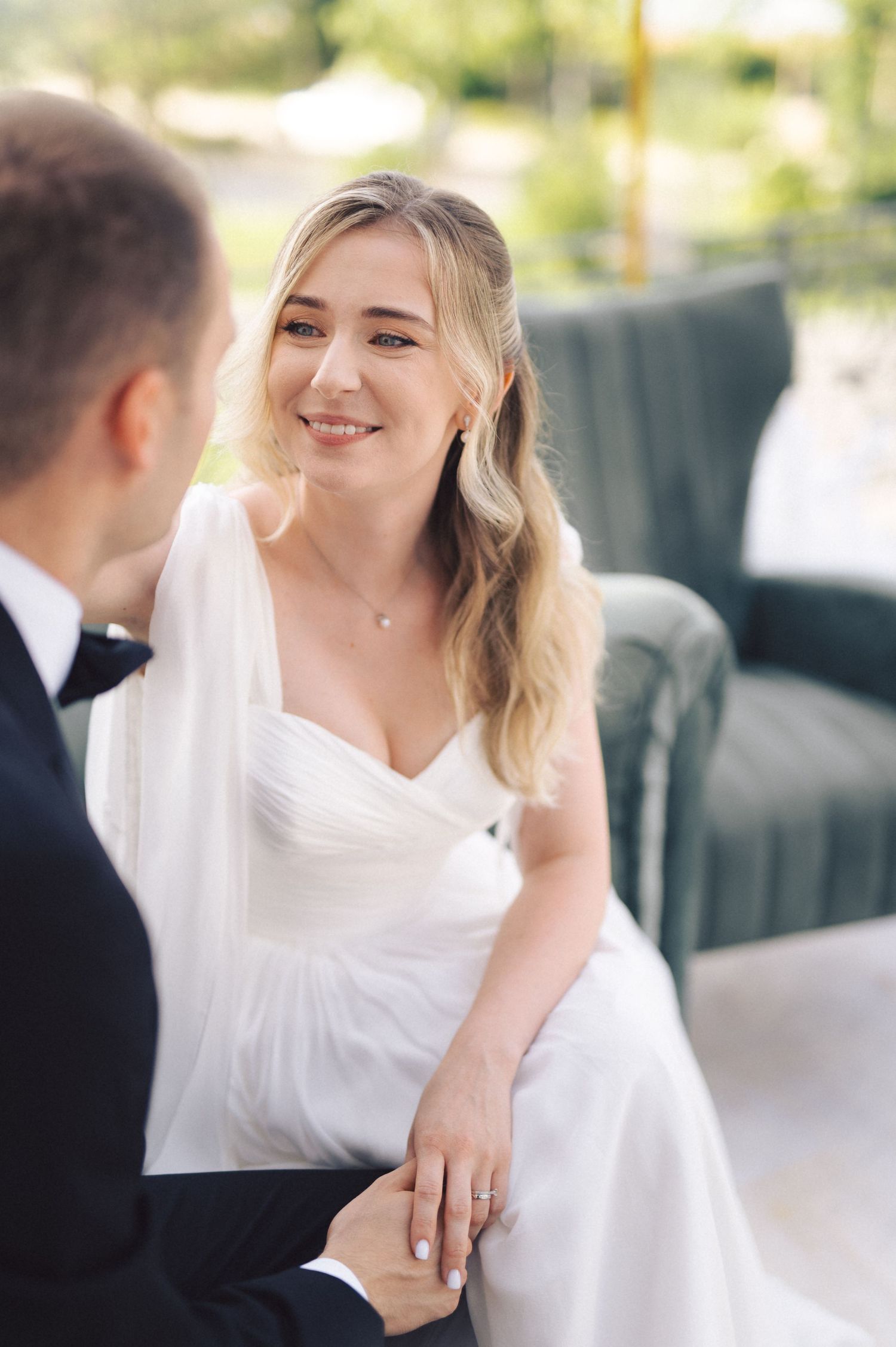 A tender moment shared between a couple on their wedding day as the bride in a white gown smiles warmly.